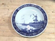 A Delft decorative wall plate depicting figures below windmill stamped verso Royal Sphinx Maastricht