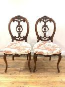 A Pair of Victorian walnut framed balloon back side chairs, the crest rail and splat of carved