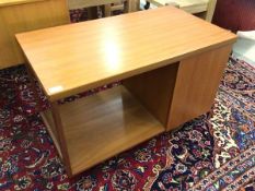 A mid century teak coffee table, the fold over revolving top above a fall front cupboard revealing