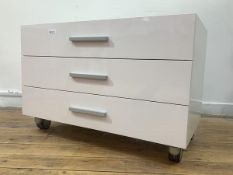 A Contemporary white laminate chest fitted with three drawers raised on castors, H57cm, W86cm,