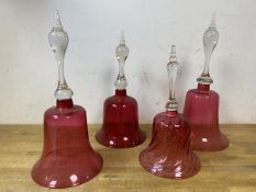 A group of four cranberry and clear glass bells, one with clapper, tallest measures 33cm high (4)