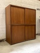 A Pair of mid century teak cupboards, formerly part of a modular wall unit, each with twin sliding