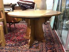 An early 20thc Arts and Crafts period oak drop-leaf table, the circular top raised on shaped