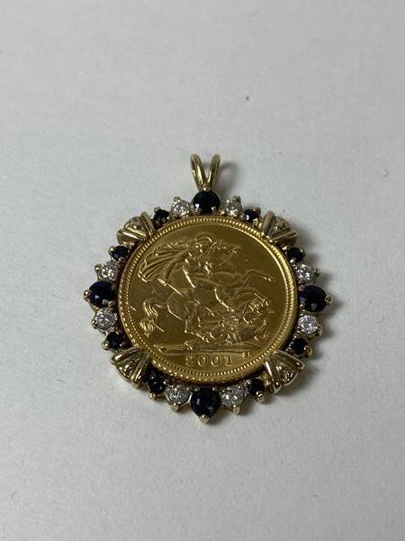A 2001 half sovereign in diamond and sapphire yellow metal mount, measures 2.5cm diameter