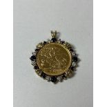 A 2001 half sovereign in diamond and sapphire yellow metal mount, measures 2.5cm diameter