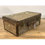 An early 20th century canvas covered travelling suitcase with remnants of old paper labels, H34cm,
