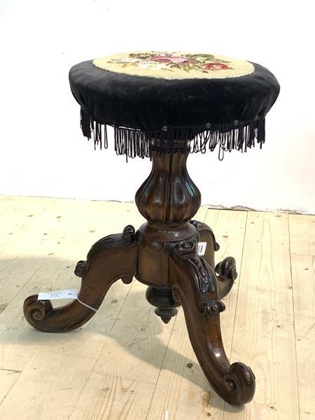 A Victorian mahogany rise and fall music stool, the circular top with floral needlework upholstery