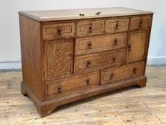 An Edwardian oak chest, fitted with four short, four long drawers and two cupboards, all with