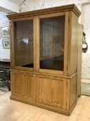 A late 19th/ early 20th century pine kitchen cabinet, the projecting cornice over two glazed doors