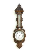 A Late Victorian aneroid barometer and thermometer in an oak floral and scroll carved banjo