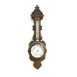 A Late Victorian aneroid barometer and thermometer in an oak floral and scroll carved banjo