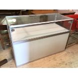 A modern jewellery display counter with glass to top and sides, sliding glass opening to back,