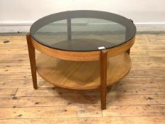 A mid century teak circular coffee table, the tinted glass top raised on square tapered supports