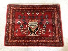 A small Persian design red ground rug, the abrashed field with stylised urn issuing foliate framed