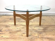 A Vintage mid century coffee table, the circular plate glass top raised on three teak turned