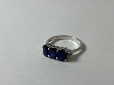 A sapphire ring marked 9ct, with three oval cut sapphires flanked by diamond chips to corners,