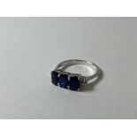 A sapphire ring marked 9ct, with three oval cut sapphires flanked by diamond chips to corners,