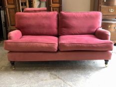 A Howard and sons style two seat sofa, with squab cushions, upholstered in a faded claret cotton