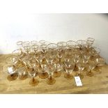 A quantity of stemware with gilt floral decoration to edges, on amber glass stems and bases,