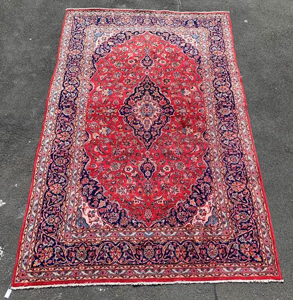 A Persian Kashan design hand knotted rug, the red field with blue medallion, spandrels and