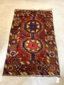A Caucasian Kazak red ground rug, coarsely woven and hand knotted, with pole medallion and repeating