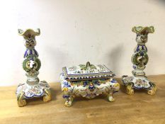 A pair of Rouen Faience candlesticks, (25cm h) and a lidded casket on scrolled supports, a/f, (3)