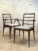 A pair of mid century teak ladder back dining chairs with open arms, upholstered seats raised on