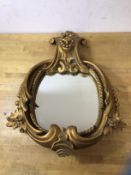 A gilt composition wall mirror with scrolling surmount over glass within C scroll and foliate gilt
