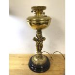 A late 19thc early 20thc oil lamp converted to electricity, the brass reservoir over a pair of young
