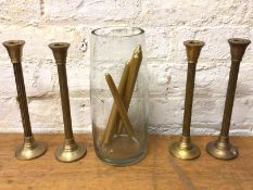 A set of four brass column style candlesticks, (29cm h) and a glass cylindrical vase (5)