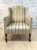 A late 19th / early 20th century wingback easy chair, upholstered in striped floral, green and ivory