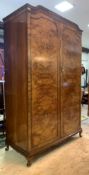 A Queen Anne style figured walnut wardrobe, the arched top over two panelled doors enclosing