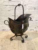 An early 20th century coal scuttle, with wrought metal handle and scrolled body enclosing a copper