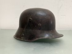 A WWI German Stalhelm M16 steel helmet with faded and worn camouflage paint, no liner or chinstrap