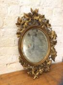 19thc wall mirror, the bevelled oval frame within a dished gilt frame, surrounded by pierced