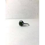 A white metal green beryl set ring with three diamonds to each shoulder, beryl approximately 2ct,