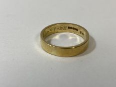 A gold wedding band, marked 18ct, inscription to interior, size T, weighs 6.58 grammes