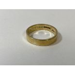 A gold wedding band, marked 18ct, inscription to interior, size T, weighs 6.58 grammes