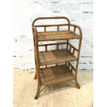 A cane and wicker open shelf with three tiers on splayed supports (89cm x 50cm x 37cm)