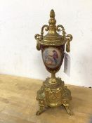 A gilt metal and china ornament of urn on stand form, urn having single panel depicting musician and