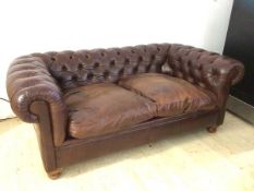 A Laura Ashley Chesterfield brown leather two seater sofa on bun feet, (69cm x 180cm x 103cm)