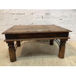 An Indonesian hardwood coffee table, metal bound, the moulded rectangular top on turned supports