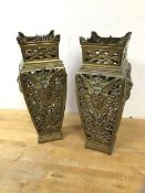 A pair of pierced brass square baluster shaped ornaments, each with sunburst to frieze above mask