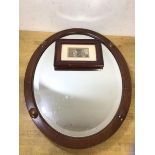 An oval wall mirror the glass with bevelled edge and mahogany frame (45cm x 35cm) and a framed