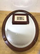 An oval wall mirror the glass with bevelled edge and mahogany frame (45cm x 35cm) and a framed