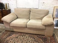 A contemporary three seat sofa upholstered in natural fabric raised on block supports, (84cm x 185cm