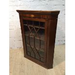 A George III mahogany corner cabinet the moulded top above frieze with inlaid shell over glazed door