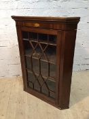 A George III mahogany corner cabinet the moulded top above frieze with inlaid shell over glazed door
