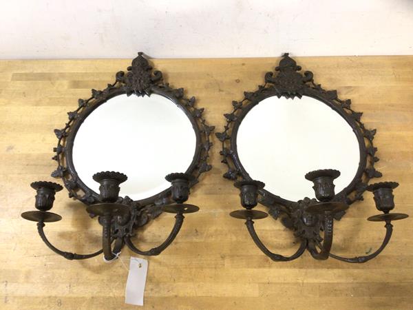 A pair of patinated metal girandole mirrors, each circular bevelled plate within frame elaborately