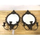 A pair of patinated metal girandole mirrors, each circular bevelled plate within frame elaborately